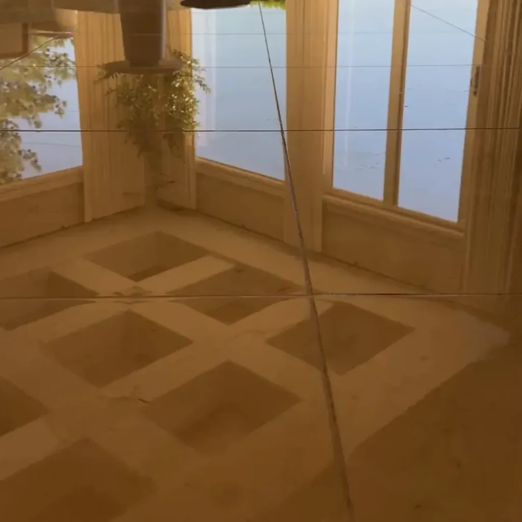 Polished marble floor with a diamond inlay pattern reflecting patio doors and curtains after marble polishing in a Las Vegas home